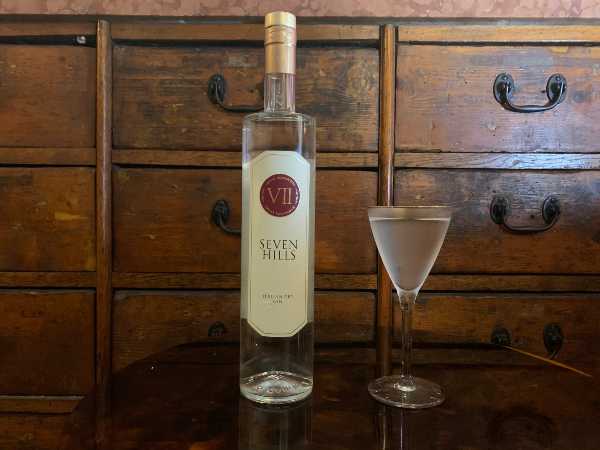 DRINK: GOLDEN MEMORIES (ispirato al film 'Una poltrona per due', di John Landis, 1983) BARTENDER: Daniele D'Ercole, bar manager di Sacripante Art Gallery di Roma INGREDIENTI: 6 cl Seven Hills Italian Dry Gin 1,5 cl vermouth dry aromatizzato alla crosta di pane 2 drops di olio evo all'origano e rosmarino Bicchiere: coppetta cocktail PREPARAZIONE: Per realizzare il vermouth dry aromatizzato: tostare 20/30 g di croste di pane e lasciarle in macerazione per 3/4 ore in 1l di vermouth dry, filtrare il tutto con un filtro a tessuto. Per realizzare l'olio evo all'origano e rosmarino: riscaldare 100 ml di olio a 60 gradi con un rametto di rosmarino e un cucchiaio di origano, lasciare a fuoco spento per 2 ore e filtrare il tutto. Una volta preparati i due homemade, si realizza il drink, con la tecnica stir & strain. Versare in un mixing glass il Seven Hills Gin e il vermouth dry alla crosta di pane, aggiungere del ghiaccio e miscelare per raffreddare il tutto. Quando ben freddo, filtrare il drink, versarlo nella coppetta precedentemente raffreddata e guarnire con 2/3 gocce di olio aromatizzato, direttamente sopra il cocktail. ISPIRAZIONE: Un twist del Martini Cocktail, realizzato da Daniele D'Ercole, bar manager di Sacripante Art Gallery, galleria d'arte e cocktail bar in via Panisperna, in pieno quartiere Monti a Roma. Il Martini Cocktail è considerato di per sé un drink signorile e nobile e in questa rivisitazione del classico viene proposto con ingredienti quali pane e olio, alimenti-base e di grande gusto, nonostante, o proprio grazie, la loro umile origine. Un drink che nasce dal ricordo personale del barman, legato alla nonna e alla sua abitudine di preparare una merenda pomeridiana di pane, olio e sale. Profumi e sapori legati a una sensazione di piacere e nostalgia, che ricordano quanto la felicità sia legata all'esperienza delle piccole cose, spesso considerate più scontate, ma che, al contrario, riempiono l'anima. Come nel classico film natalizio, "Una poltrona per due", il drink è la prova che 'l'abito non fa il monaco', sottolineando quanto il valore di una persona si ottenga dalle cose più modeste e dalle esperienze passate. Come il ladruncolo buono, interpretato da Eddie Murphy, diventa broker, qui il pane e l'olio, insieme al fantastico e già perfetto Seven Hills Gin, realizzato con botaniche romane, si trasformano in un drink nobile e da meditazione, per i migliori momenti della nostra vita.
